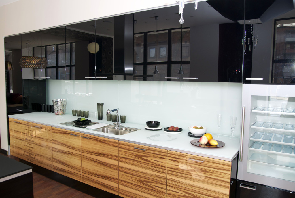 Moderní kuchyně v černé barvě se dřevěným dekorem a bílou pracovní deskou.