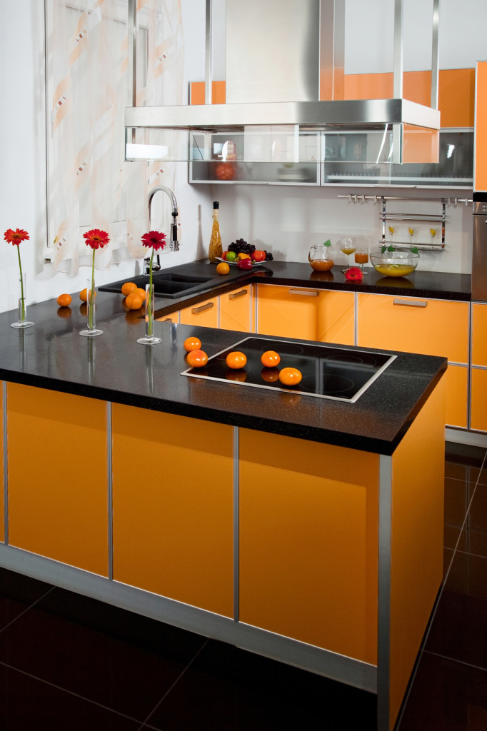 Moderní kuchyně v oranžové barvě a černou pracovní deskou.